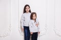 Two adorabile littel girl in sweater and jeans, posing together on white background, smiling. Posing in studio. Royalty Free Stock Photo