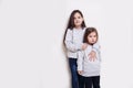 Two adorabile littel girl in sweater and jeans, posing together on white background, smiling and looking at camera. Royalty Free Stock Photo