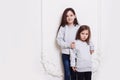 Two adorabile sisters posing together on white background, smiling and looking at camera. Royalty Free Stock Photo