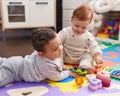 Two adorable babies playing with toys sitting on floor at kindergarten Royalty Free Stock Photo