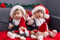 Two adorable babies sitting on sofa playing with santa claus doll at home Royalty Free Stock Photo