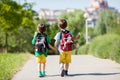 Two adorable boys in colorful clothes and backpacks, walking away, holding and eating ice cream