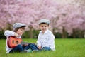 Two adorable caucasian boys in a blooming cherry tree garden, pl Royalty Free Stock Photo