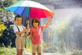 Two adorable children, boy brothers, playing with colorful umbrella under sprinkling water Royalty Free Stock Photo