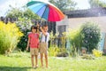 Two adorable children, boy brothers, playing with colorful umbrella under sprinkling water Royalty Free Stock Photo