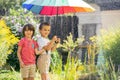 Two adorable children, boy brothers, playing with colorful umbrella under sprinkling water Royalty Free Stock Photo