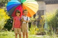 Two adorable children, boy brothers, playing with colorful umbrella under sprinkling water Royalty Free Stock Photo