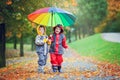 Two adorable children, boy brothers, playing in park with umbrella