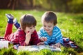 Two adorable cute caucasian boys, lying in the park in a fine su