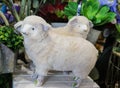 Two adorable decorative fabric and fur spring lambs in front of plants - selective focus