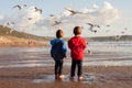 Two adorable kids, feeding the seagulls on the beach