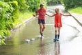 Two adorable kids are playing with paper boats in a stream after rain on a city sidewalk Royalty Free Stock Photo