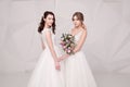 Two adorable ladies wearing in long fashionable dresses holding flowers Royalty Free Stock Photo