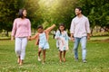 Two adorable little girls walking outside at park with parents. Sibling sisters out for a walk outdoors with their Royalty Free Stock Photo