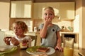 Two adorable little kids eating toasted bread with chocolate butter while having breakfast in the kitchen Royalty Free Stock Photo
