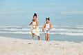 Two adorable little mixed race girls running and having fun at the beach. Two sibling sisters playing on the shore Royalty Free Stock Photo