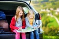 Two adorable little sisters exploring a map before going on vacations with their parents Royalty Free Stock Photo