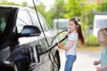 Two adorable little sisters washing a car on a carwash