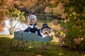 Two adorable little thankful Thanksgiving Pilgrim Dogs in wagon near river