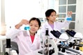 Two adorable pretty schoolgirls in lab coat doing simple science experiments, young Asian kid scientist having fun in chemistry Royalty Free Stock Photo