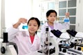 Two adorable pretty schoolgirls in lab coat doing simple science experiments, young Asian kid scientist having fun in chemistry Royalty Free Stock Photo