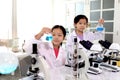 Two adorable pretty schoolgirls in lab coat doing simple science experiments, young Asian kid scientist having fun in chemistry Royalty Free Stock Photo