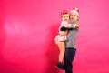 Two adorable siblings, boy and little girl, in Santa hats lovingly hug each other, on pink background