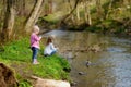 Two adorable sisters feeding ducks by a river Royalty Free Stock Photo