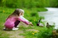 Two adorable sisters feeding ducks by a river Royalty Free Stock Photo