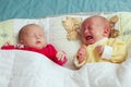 Two adorable twin babies sleeping, one crying. Closeup portrait, caucasian child