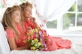 Two adorable twin sisters in beautiful pink dresses with bouquet