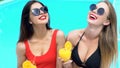 Two adorable women clinking cocktails on swimming pool party, luxury resort Royalty Free Stock Photo