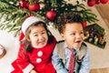 Two adorable 3 year old kids playing by the Christmas tree