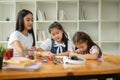 Two adorable young Asian kindergarten girls are focusing on studying art with a teacher Royalty Free Stock Photo