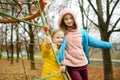 Two adorable young girls having fun on a playground together in beautiful autumn park. Cute sisters playing outdoors in late