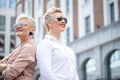 Two adult Businesswoman boss posing back to back near office building