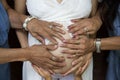 Of two adult females and one kid touching the belly of a pregnant woman