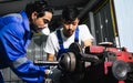 Two adult handsome male mechanics wearing uniform, using machine for fix, repair car or automobile components, teamwork helping, Royalty Free Stock Photo