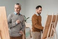 two adult male artists painting on easels