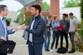 two adult men on campus passing papers Royalty Free Stock Photo