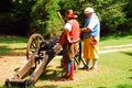 Two adult men demonstrate firing a Colonial era cannon