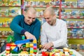 Two adult men with happy faces create colorful constructions of toy bricks. Two adult men build of plastic blocks. Royalty Free Stock Photo