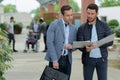 two adult men on university campus looking at folder