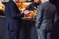 Two adult successful businessmen discuss and talk about business deal in the bar while they drinking at the evening.