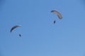 Two adventurous people flying in the bright blue sky with parachutes