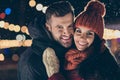 Two affectionate people in central park party at x-mas celebration standing close wear winter jackets scarfs and knitted