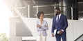 Two black coworkers chatting outdoors near office building