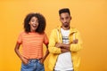 Two african american friends standing over orange background, girl thinks idea is awesome feeling excited and joyful