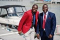 Two african american happy successful mans at suit. Rich black business mans against yacht