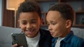 Two African American little boys brothers laughing browsing mobile phone without parents bad behavior young generation Royalty Free Stock Photo